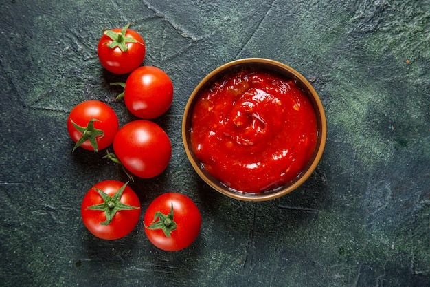 Vista superior de tomates rojos frescos con pasta de tomate en superficie oscura
