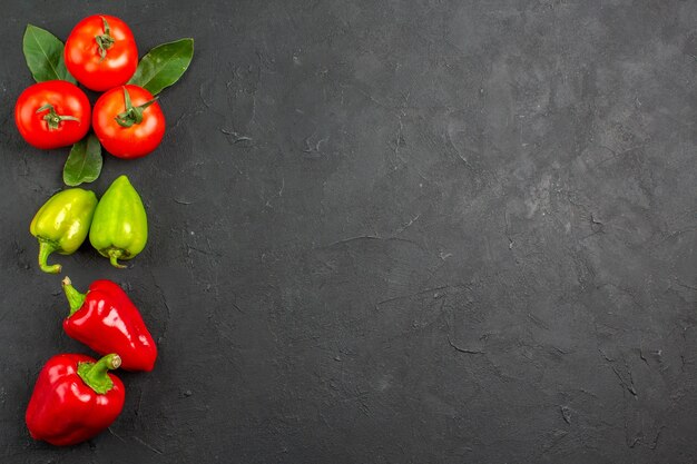 Vista superior de tomates rojos frescos con pimientos en ensalada de color de mesa oscura madura