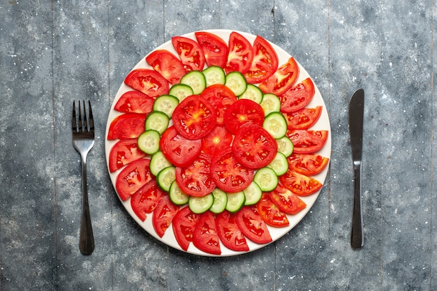 Vista superior de tomates rojos frescos en rodajas ensalada fresca en el escritorio gris