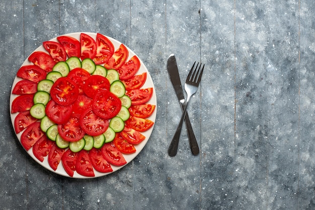 Foto gratuita vista superior de tomates rojos frescos en rodajas ensalada fresca en el escritorio gris