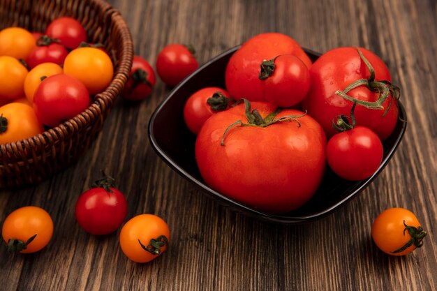 Vista superior de tomates rojos de gran tamaño en un recipiente en una pared de madera