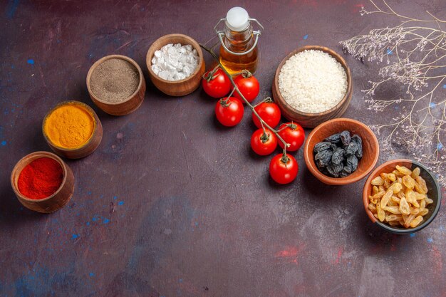 Vista superior de tomates rojos con pasas y condimentos sobre fondo oscuro salud ensalada de verduras con pasas