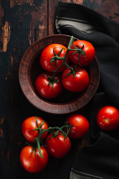 Vista superior de tomates rojos con tallo en un tazón