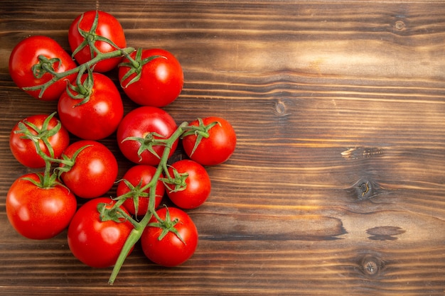 Vista superior de tomates rojos verduras maduras en el escritorio de madera marrón