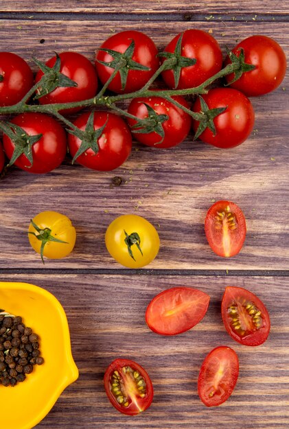 Vista superior de tomates con semillas de pimienta negra sobre superficie de madera