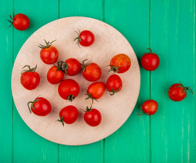 Vista superior de tomates en la tabla de cortar en superficie verde