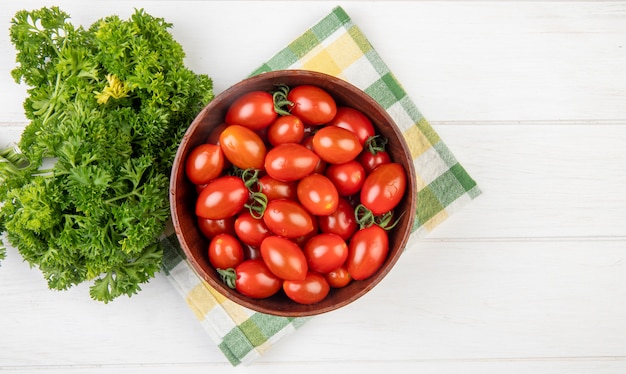 Foto gratuita vista superior de tomates en un tazón con cilantro chino sobre tela y superficie de madera con espacio de copia