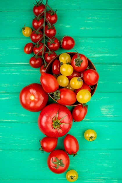 Vista superior de tomates en un tazón con otros en superficie verde