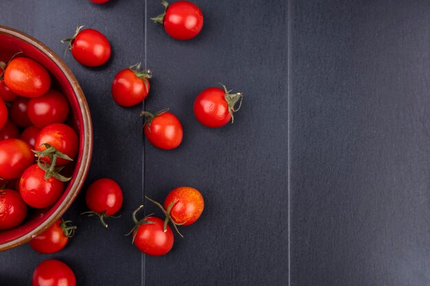 Vista superior de tomates en un tazón y sobre una superficie negra