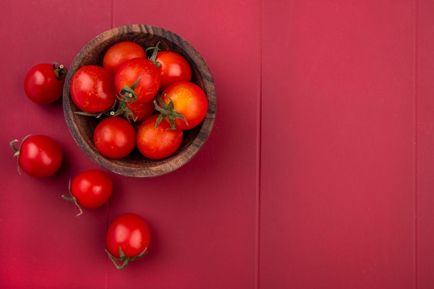 Vista superior de tomates en un tazón y sobre superficie roja