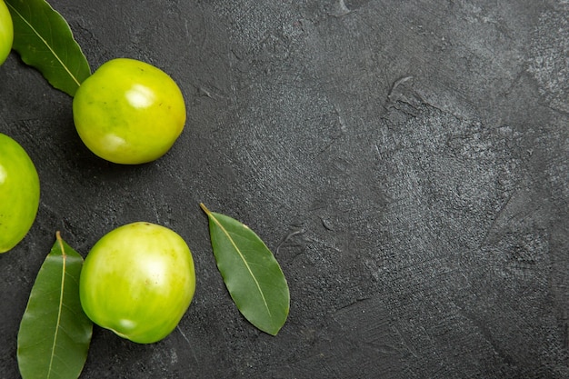 Vista superior de tomates verdes hojas de laurel a la izquierda de la superficie oscura