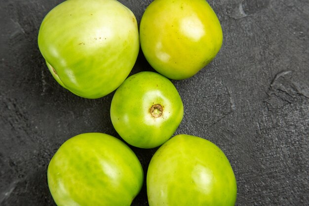 Vista superior de tomates verdes en mesa oscura con espacio de copia