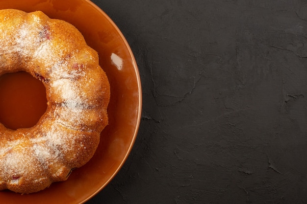 Foto gratuita una vista superior de la torta de cereza redonda dentro de la placa marrón sobre la mesa oscura pastel de galleta dulce de azúcar