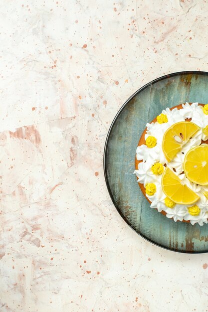 Vista superior de la torta con crema pastelera blanca y rodajas de limón en un plato redondo