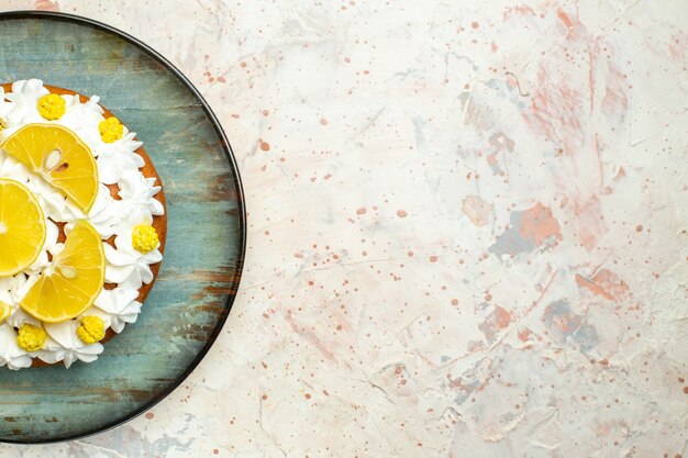 Vista superior de la torta con crema pastelera blanca y rodajas de limón en un plato redondo