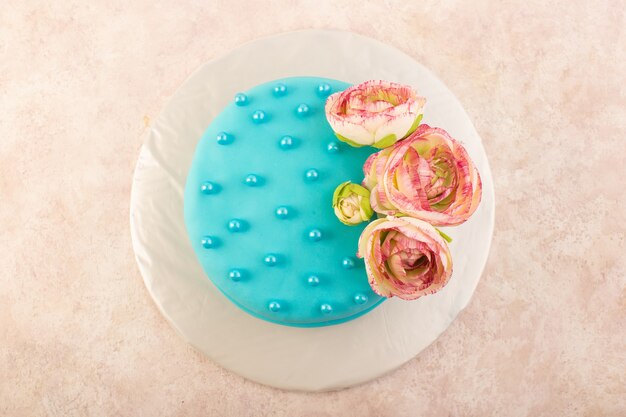 Una vista superior de la torta de cumpleaños azul con flores en la parte superior del escritorio gris celebración fiesta cumpleaños color
