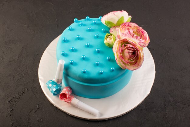 Una vista superior de la torta de cumpleaños azul con flores en la parte superior del escritorio oscuro fiesta de celebración de cumpleaños