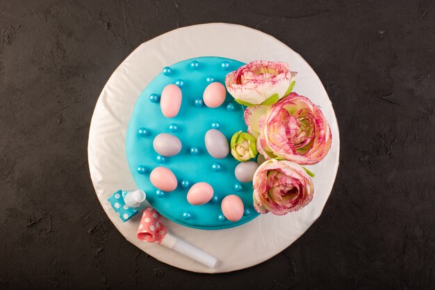 Una vista superior de la torta de cumpleaños azul con flores en la parte superior de la mesa gris pastel de cumpleaños fiesta de celebración