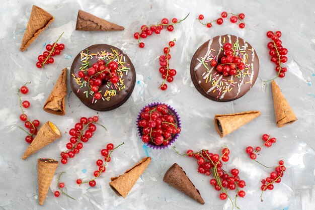 Una vista superior de tortas de chocolate con rosquillas diseñadas con frutas sobre el fondo blanco pastel biscuit donut choco