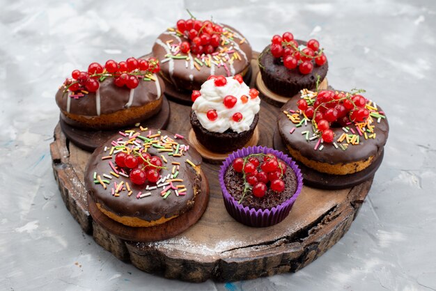 Una vista superior de tortas de chocolate con rosquillas diseñadas con frutas sobre el fondo blanco pastel biscuit donut chocolate