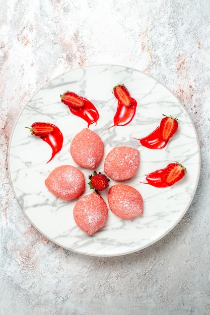 Vista superior tortas de fresa rosa pequeños dulces sobre fondo blanco pastel galleta té fruta galleta azúcar dulce