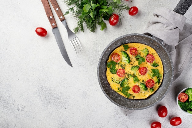 Vista superior de la tortilla de desayuno en sartén con tomates y copia espacio