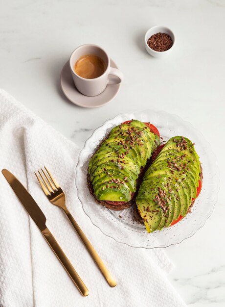 Vista superior de tostadas de aguacate en plato con cubiertos y café