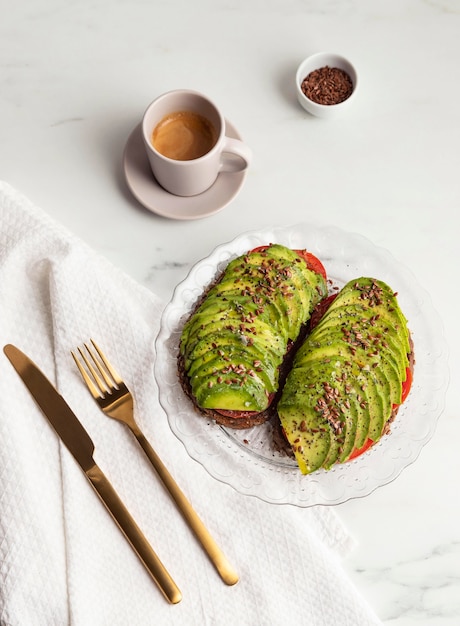 Vista superior de tostadas de aguacate en plato con cubiertos y café