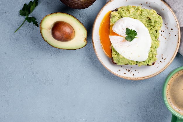 Vista superior de tostadas de aguacate en un plato con huevo escalfado y taza de café