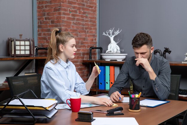 Vista superior de trabajadores calificados trabajadores y motivados que intercambian ideas sobre un tema importante en la oficina