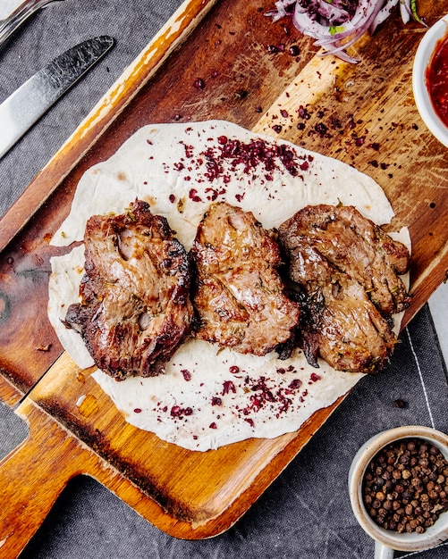 Foto gratuita vista superior de trozos de carne asada en una tabla de madera