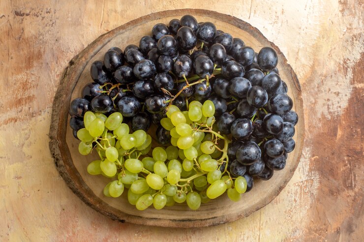 Foto gratuito vista superior de la uva racimos de uvas verdes y negras en la tabla de cortar