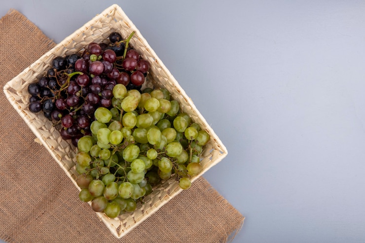 Foto gratuito vista superior de uvas en canasta de cilicio sobre fondo gris con espacio de copia