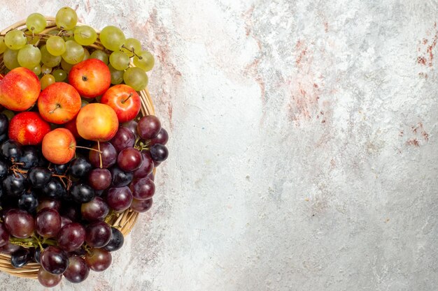 Foto gratuita vista superior de uvas frescas con ciruelas sobre superficie blanca