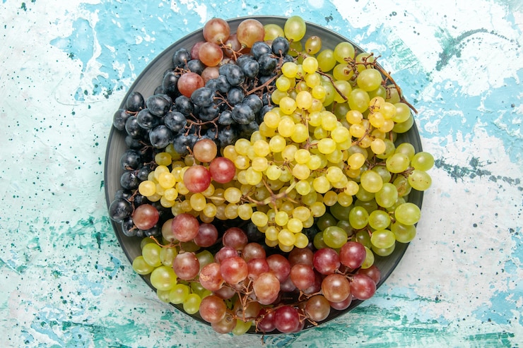 Foto gratuito vista superior de uvas frescas de color fruta jugosa y suave en la superficie azul claro fruta baya vino de jugo suave fresco