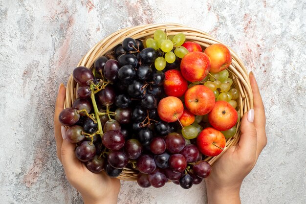 Vista superior de uvas frescas dentro de la canasta sobre superficie blanca