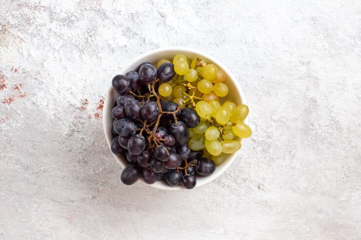Foto gratuito vista superior de las uvas frescas dentro de la placa en la superficie de la luz vino de frescura suave jugosa fruta