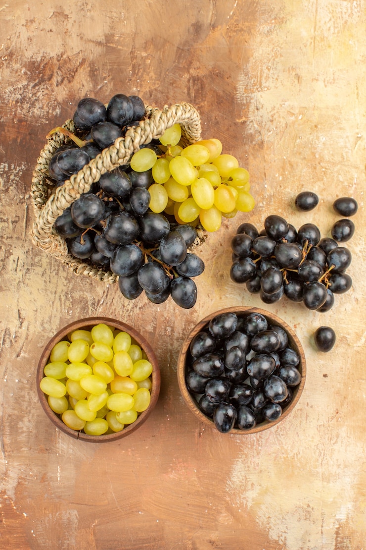 Foto gratuito vista superior de uvas frescas negras y amarillas en pequeñas macetas de madera marrón en la canasta y