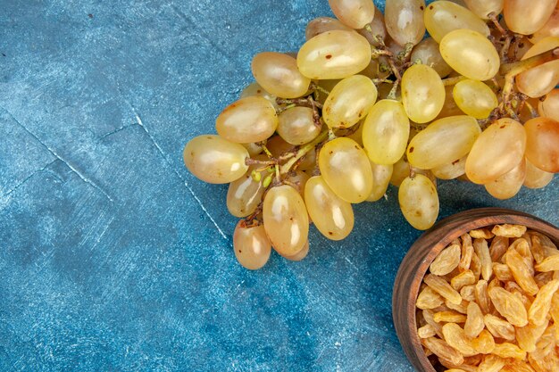 Vista superior de uvas frescas con pasas en mesa azul