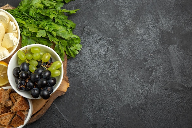 Vista superior de uvas frescas con queso verde y rodajas de limón en la superficie oscura comida fruta leche comida