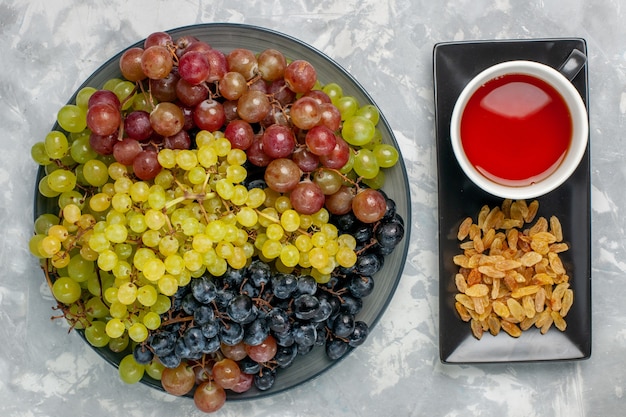 Vista superior de uvas frescas con taza de té y pasas en uva de té fresco de fruta de superficie blanca