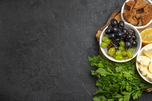 Vista superior de uvas frescas con verduras de queso blanco y limón en la superficie oscura comida fruta leche comida