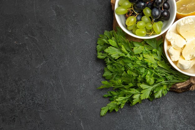 Vista superior de uvas frescas con verduras de queso blanco y limón en la superficie oscura comida fruta leche comida