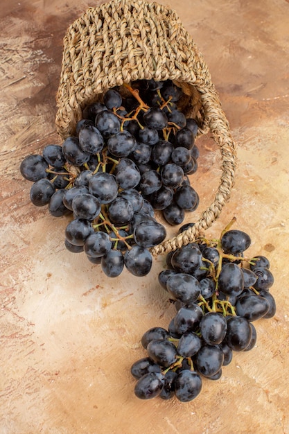 Vista superior de uvas negras frescas dentro de la cesta sobre fondo claro