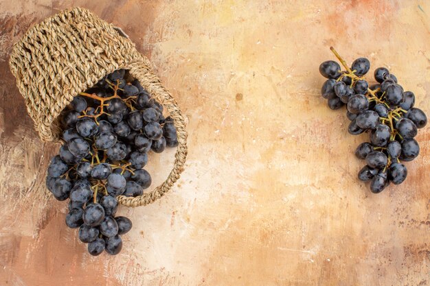 Vista superior de uvas negras frescas dentro de la cesta sobre fondo claro