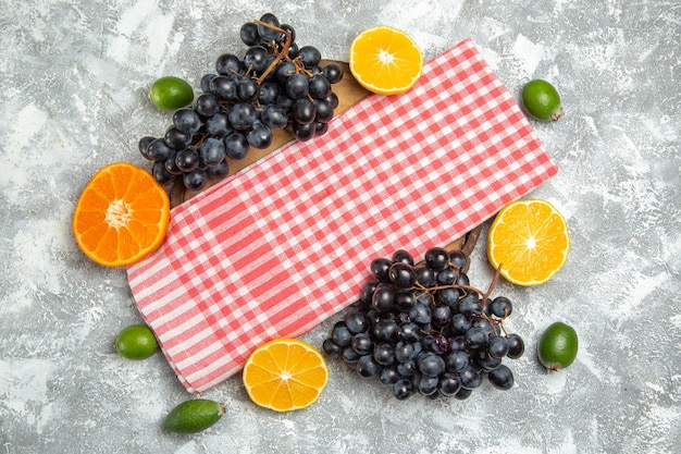 Vista superior de uvas negras frescas con feijoa y naranjas sobre fondo blanco fruta madura fresca suave