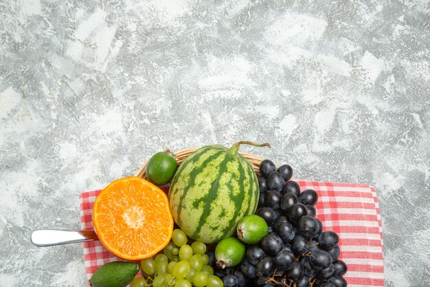 Vista superior de uvas negras frescas con naranja y feijoa en superficie blanca clara fruta suave madura fresca