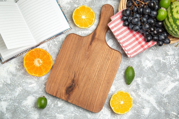 Vista superior de uvas oscuras frescas con naranjas y sandía en la superficie blanca fruta madura árbol suave vitamina fresca