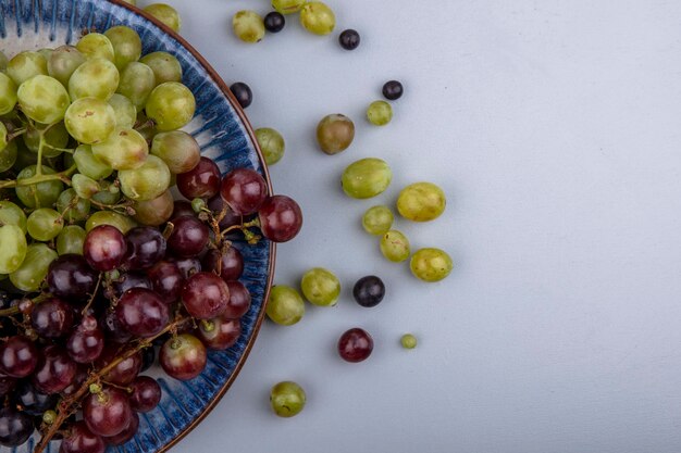 Vista superior de uvas en placa y sobre fondo gris con espacio de copia