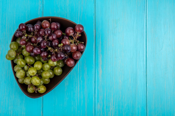 Foto gratuito vista superior de uvas en un recipiente sobre fondo azul con espacio de copia